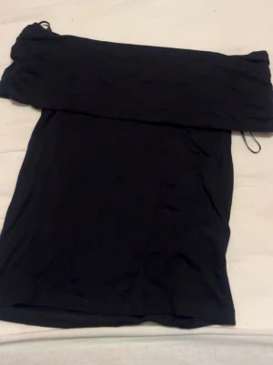 Svart offshoulder topp - En svart offshoulder topp i mjukt tyg. Enkel och stilren design som passar till många olika outfits. Toppen är ärmlös och har en bred kant upptill som sitter snyggt över axlarna. Från newyorker knappt använd. Storlek Xs 🙌 pris kan diskuteras. 