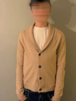 Beige kofta med sjalkrage - xs/s funkar perfekt 👌 för dig mellan 1,80/1,70Säljer en stilren beige kofta med sjalkrage och knäppning framtill. Koftan är stickad och har långa ärmar samt ribbade muddar. Perfekt för lager-på-lager och passar till jeans eller chinos.