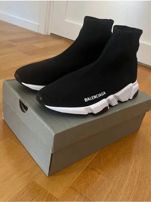  Speed Trainer sneakers svart - Svarta  Speed Trainer sneakers med vit och svart chunky sula. Stickad ovandel i syntetmaterial som sitter tight runt foten och ankeln. Logotypen syns på sidan och bak på sulan. Platt sula och modern design som sticker ut.