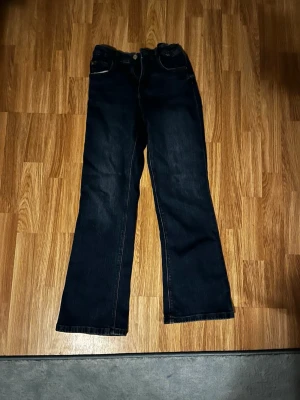 Blå flare jeans från Zara, strl 164 - Säljer ett par blåa flare jeans från Zara i storlek 164. Jeansen har klassisk femficksdesign, normal passform upptill och utsvängda ben. Materialet är mjukt denim i bomull och de har en snygg mörkblå tvätt. Perfekta för dig som gillar retrovibbar och vill ha något trendigt.