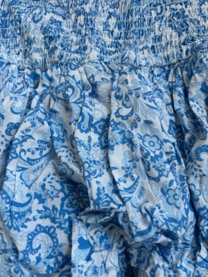 Blåvit kortklänning med volanger - Supersöt blåvit kortklänning med smock upptill och flera lager volanger nedtill. Kan se lite liten ut men den är jättestrechig!! Endast använd en gång🩵🩵