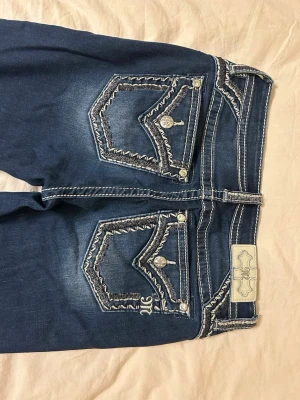 Miss Me Jeans - Skitsnygga miss me jeans strl 28 (ungefär m), mid/low-waist, lite för korta i benen på mig som är ca 180cm. Coola detaljer fram och bak. En liten defekt på främre låret där en tråd dragits fram men går enkelt att fixa (syns knappt på sista bilden)🩷  Köpta för ~1000kr  Öppen för prisförslag! Skriv vid fler frågor ☺️
