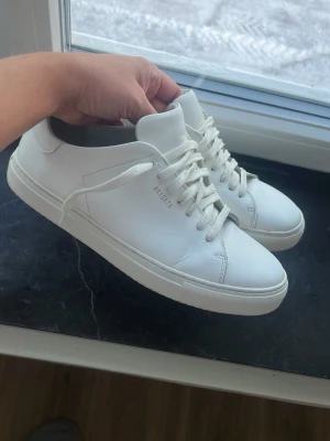 Vita sneakers från Axel Arigato säljes billigt!  - Säljer ett par stilrena vita sneakers från Axel Arigato. Skorna har klassisk låg profil, rund tå och snörning. Tillverkade i slätt skinn med diskret logga på sidan. Perfekta för dig som gillar minimalistisk och clean stil. Storlek 42.  OBS NYPRIS: 2650 SEK! 