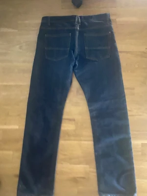 Mörkblå raka jeans - Säljer ett par mörkblå jeans med klassisk femficksdesign och raka ben. Jeansen har normal passform och är tillverkade i ett robust denimtyg. Perfekta för dig som gillar en enkel och tidlös look.