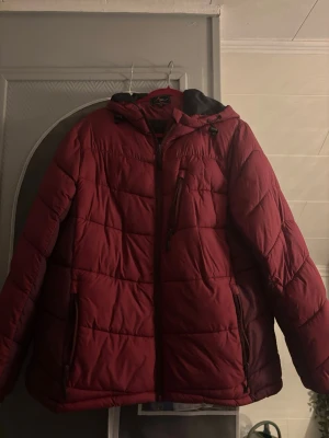 Vinröd pufferjacka High Mountain - Säljer en vinröd pufferjacka från High Mountain i damstorlek 46. Jackan har huva, dragkedja framtill och flera praktiska fickor med dragkedja. Perfekt för kalla dagar och har en schysst quiltad look. Materialet är syntet och jackan är riktigt varm och skön. 