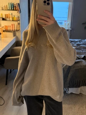 Filippa K stickad tröja – ull & cashmere - Säljer en stilren och tidlös stickad tröja från Filippa K. Tillverkad i en lyxig och mjuk kvalitet med 70% ull och 30% cashmere, vilket gör den både varm och behaglig att bära.  Skick: Bra begagnat skick. Det finns en liten fläck på ärmen/handen som syns i vissa ljus, men inget man tänker på vid användning (se bild). I övrigt fin.