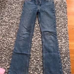 Blå bootcut jeans från Gina - Säljer ett par klassiska blå jeans från gina i storlek 34. Jeansen har bootcut-modell med raka ben och normal passform. Tillverkade i jeansmaterial med snygga detaljer och femficksdesign. Perfekta för en chill och stilren look.