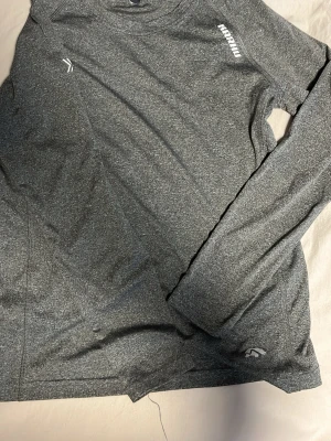 Mörkgrå långärmad träningströja Karhu - Säljer en mörkgrå långärmad träningströja från Karhu i storlek S. Tröjan är tillverkad i ett mjukt och stretchigt syntetmaterial som andas, perfekt för aktiva dagar. Diskret logga på bröstet och vid nederkanten. Enkel och sportig design. Väldigt luftigt material som är tunt och andas!!