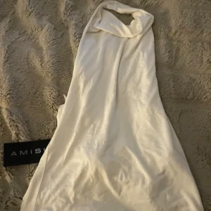 Vit halterneck topp från Amisu - Säljer en snygg vit halterneck topp från Amisu. Toppen är ärmlös och har en hög halsringning som knyts i nacken. Tillverkad i mjukt och stretchigt material som sitter skönt på kroppen. Perfekt för dig som gillar stilrena och trendiga plagg.