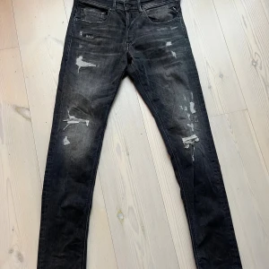Replay svarta skinny jeans med slitningar - Svarta skinny jeans från Replay E29 L32. coola slitningar och distressed detaljer på både lår och knän. Jeansen har klassisk femficksdesign,  tillverkade i stretchigt denim för en tight passform. Perfekta för en edgy streetstil.