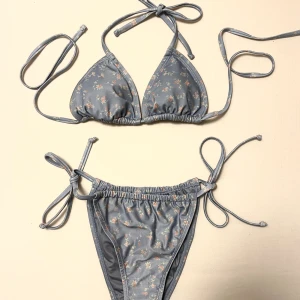 NA-KD blåblommig bikini - Blå bikini med småblommigt mönster från NA-KD. Aldrig använd, endast lappar bortklippta. Den är jättefin och är perfekt till sommaren!