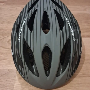 Grå och svart cykelhjälm Dunlop - Snygg cykelhjälm från Dunlop i grått och svart med coola ränder. Ventilerad design med flera öppningar och justerbart spänne för perfekt passform. Tillverkad i lätt syntetmaterial med mjuk insida och nät för extra komfort.