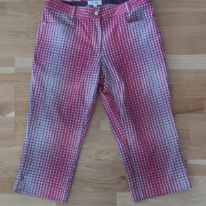 Calvin Klein byxor - Snygga rutiga byxor från Calvin Klein i rött och vitt. Modellen har raka ben med klassisk knapp med CK-logo.