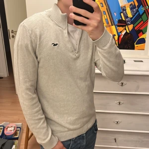 Ljusgrå half zip tröja Hollister M - Snygg ljusgrå stickad tröja från Hollister med half zip och ribbad krage. Tröjan har lång ärm och klassisk Hollister-logga broderad på bröstet. Perfekt för dig som gillar enkel och stilren look. Passar dig som vill ha en normal passform. Storleken är M och passar mig bra (se bild 5) hör av dig gällande frågor och passar även bra till mina nudie jeans i min profil! Riktigt bra skick!!🤩🤩😎