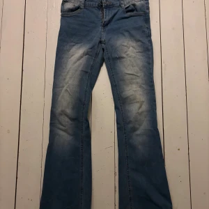Blå bootcut jeans med slitningar - Snygga blå jeans med bootcut passform och coola slitningar framtill. Klassisk femficksmodell med dragkedja och knapp. Perfekta för dig som gillar en avslappnad och trendig stil.