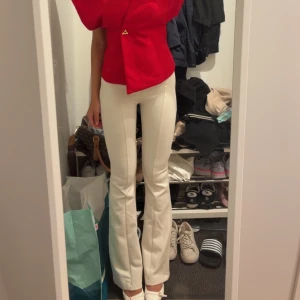 Vita bootcut byxor med hög midja - Snygga vita byxor med bootcut som är midwaist. Byxorna har en figurnära passform upptill och utsvängda ben, vilket ger en trendig siluett. Perfekta att styla med klackar eller sneakers. Materialet känns mjukt och stretchigt för extra komfort. Aldrig använd och har prislapp kvar
