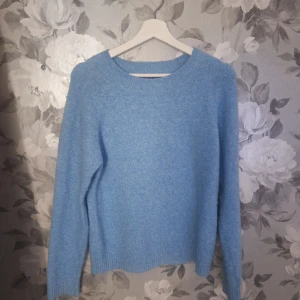 Ljusblå stickad tröja från Vero Moda - Supermysig ljusblå stickad tröja från Vero Moda. Tröjan har rund halsringning, ribbade muddar och lång ärm. Perfekt att slänga på sig när det är kyligt ute. Enkel och stilren design som är lätt att matcha med jeans eller kjol.