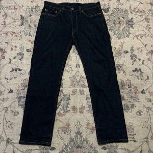 Levi's 514 mörkblå jeans W31 L30 - Mörkblå Levi's 514 jeans med klassisk femficksdesign och raka ben. Snygga kontrastsömmar och läderpatch bak i midjan. Perfekta för dig som gillar en tidlös och clean look. Tillverkade i slitstarkt denimtyg.