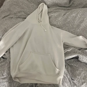 Vit hoodie med huva och ficka - Säljer en enkel och clean vit hoodie med stor magficka och snörning i huvan. Tröjan har lång ärm och är perfekt för chill dagar. Passformen är loose och materialet känns mjukt och skönt mot huden.