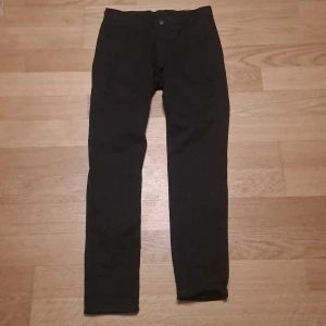 Svarta slim fit byxor Hampton Republic - Svarta slim fit byxor från Hampton Republic med comfort stretch för extra bekvämlighet. Klassisk design med knapp och dragkedja framtill. Perfekta för dig som gillar en smalare passform och stilren look.