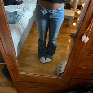 Blå bootcut jeans - Snygga blå jeans från Gina i storlek 36. Modellen har bootcut-ben och låg midja, med en slitning på ena knät. Bra skick! 