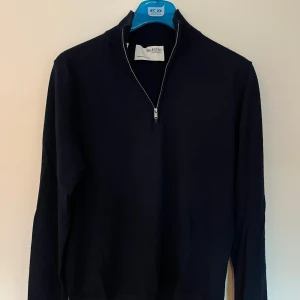 Svart half zip tröja från Selected Homme - Svart långärmad tröja från Selected Homme med stilren half zip-dragkedja i halsen. Tröjan har en klassisk passform och är tillverkad i mjukt material som passar perfekt till lager-på-lager. Enkel och snygg design utan mönster.