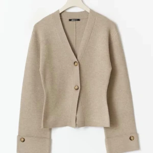 Beige kofta från Gina Tricot - Säljer en stilren beige kofta från Gina Tricot med v-ringning och två knappar framtill. Köpte den men har knappt använt pris kan diskuteras 💞