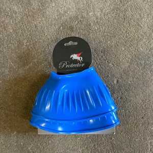 Blåa gummiboots från Protector - Säljer ett par blåa gummiboots från Protector, perfekta för ridning. De är tillverkade i slitstarkt syntetmaterial och har en räfflad design för extra grepp. Snygg och funktionell accessoar till hästen. Helt nya. 