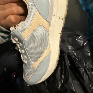 Beige och ljusblå chunky sneakers - Snygga chunky sneakers i beige och ljusblått med meshpaneler och detaljer i syntetmaterial. Skorna har rund tå, platt sula och klassisk snörning. Perfekt för dig som gillar en sportig och fräsch stil med lite retrovibe.