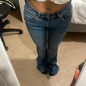 Blå bootcut jeans från Levis - Säljer ett par klassiska blå lager 157 jeans med bootcut passform och låg midja. Jeansen har fem fickor, orangea sömmar och slitna detaljer vid benslut. Perfekt för dig som är över 165 cm lång. Jag själv är 150 cm och jeans sitter långa på mig💞