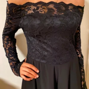 Svart offshoulder spetsklänning - Supersnygg svart långklänning med offshoulder och långärmade spetsdetaljer. St L men passar även S, M