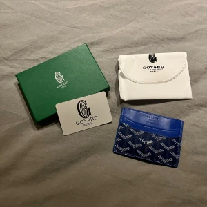 Blå Go4ard plånbok med mönster - Säljer en snygg blå plånbok från Go4ard med ikoniskt mönster i vitt. Plånboken är kompakt och perfekt för kort, med flera fack och klassisk Go4ard-logga framtill. Levereras med originalförpackning och dustbag.