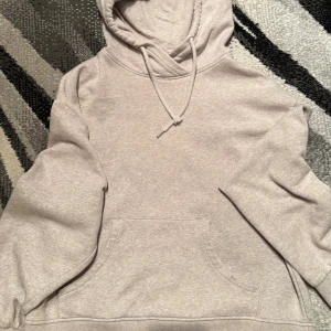 Beige hoodie från Lindex med huva - Säljer en beige hoodie från Lindex i storlek M. Tröjan har en stor känguruficka framtill, snörning vid huvan och mjukt fleecefoder på insidan. Perfekt för chill dagar och har en relaxed passform med långa ärmar.
