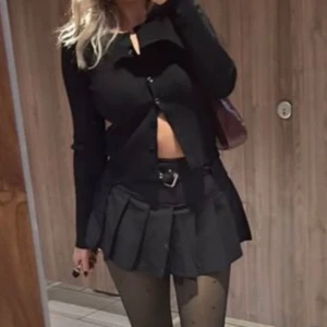 Svart croppad ribbad topp med knappar - Säljer en svart croppad topp med långa ärmar och snygg ribbad struktur. Toppen har knappar framtill och sitter tight mot kroppen