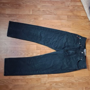 Svarta jeans från Davy's Jeanswear - Svarta jeans från Davy's Jeanswear med klassisk femficksdesign och raka ben. Jeansen har läderpatch bak i midjan och tydliga sömmar. Materialet är robust denim som ger en tidlös look. Perfekta för dig som gillar en enkel och clean stil.