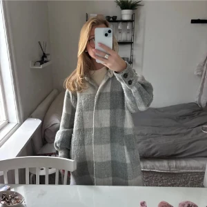 Gråvit rutig kappa - Lång och rutig kappa i grått och vitt med stora knappar framtill. Jackan har mjukt ull-liknande material och klassisk krage. Perfekt för lager-på-lager och chill stil. Snyggt rutmönster och knappdetalj vid handlederna. Knappt använd.💕