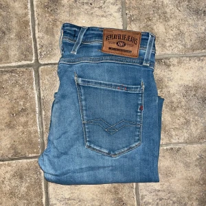 Replay anbass jeans  - Snygga Replay Anbass Jeans i klassisk blå färg med raka ben och normal passform. Jeansen har fem fickor, tydliga sömmar och ett brunt Replay-märke bak i midjan. Midja 37cm, längd 85cm UPPSYDDA För att passa L28/L30 så kolla måtten noggrant, se en fläck på bild 5. Ifall det inte finns någon bild i annonsen där jag bär plagget så är det för att jag ej kan ha storleken heller passformen, så kolla måtten för storlek och googla på modellnamnet för passform 😉S4