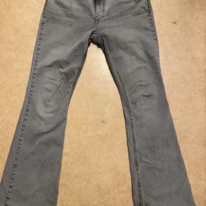 Grå bootcut jeans med utsvängda ben - Snygga grå jeans med bootcut och utsvängda ben. Klassisk femficksmodell och normal passform. Jeansen har en ljusgrå tvätt och är tillverkade i mjukt denimtyg. Perfekta för dig som gillar retrovibbar och vill sticka ut lite extra. 