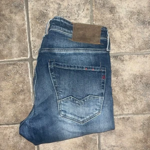 Replay Waitom jeans  - Snygga Replay Waitom jeans i klassisk blå tvätt med diskreta slitningar och raka ben. Jeansen har fem fickor, läderpatch bak och coola kontrastsömmar. Tillverkade i bomull för en skön känsla och passform. Midja 38cm, längd 105cm.  Ifall det inte finns någon bild i annonsen där jag bär plaggen jag säljer så är det för att jag ej kan ha storleken heller passformen, så kolla måtten för storlek och googla på modellnamnet för passform 😉 s4