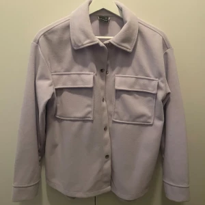 Ljuslila overshirt med fickor - Säljer en ljuslila jacka från ginatricot. Storlek XXS men är oversized och passar även en XS. 