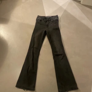 Bootcut svarta jeans från Blue Ridge - Svarta jeans från Blue Ridge med bootcut passform och klassisk femficksdesign. Jeansen har mid midja, dragkedja och knapp framtill samt snygga röda sömdetaljer på insidan. Materialet är slitstarkt jeans och insidan har mönstrat foder med stjärnor.