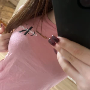 Rosa Calvin Klein t-shirt i bomull - Säljer en rosa t-shirt från Calvin Klein Jeans med klassisk CK-logga på bröstet. T-shirten är i mjuk bomull, har rund hals och korta ärmar. Sitter snyggt och figurnära, perfekt till jeans eller tights.