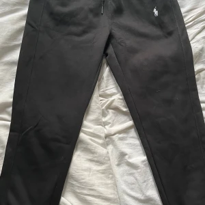 Svarta mjukisbyxor Polo Ralph Lauren - Hej!  Säljer Svarta mjukisbyxor från Polo Ralph Lauren med klassisk broderad logga i vitt på ena benet. Byxorna har resår i midjan och är gjorda i mjukt bomullsmaterial för maximal komfort. Perfekta för en chill och avslappnad stil.  Byxorna är märkta som storlek M men passar bäst för dig som vanligtvis använder storlek S.  Vill du veta något mer eller vill ha fler bilder så är det bara att skriva! Priset är såklart inte hugget i sten!