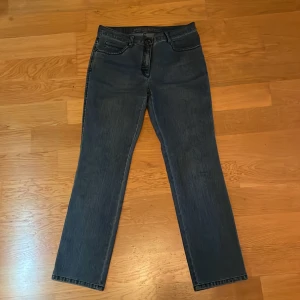 Mörkblå jeans från Brax med broderi - Snygga mörkblå jeans från Brax med raka ben och klassisk femficksdesign. Baksidan har broderade detaljer på bakfickorna som ger extra stil. Jeansen är tillverkade i denim och har en normal passform. Perfekta för dig som gillar en enkel men ändå unik look. Pris kan diskuteras 