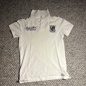 Vit vintage pikétröja från Peak Performance - Snygg vit pikétröja från Peak Performance med broderade detaljer och logga på bröstet. Klassisk krage och korta ärmar, perfekt för en clean och sportig stil. Skön och snygg piké 