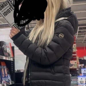 Colmar jacka - Säljer en svart pufferjacka från Colmar med klassisk quiltad design och dragkedja framtill. Jackan har hög krage, två sidofickor med dragkedja och en snygg badge på ärmen. Perfekt för kalla dagar och riktigt skön att bära. Äkta