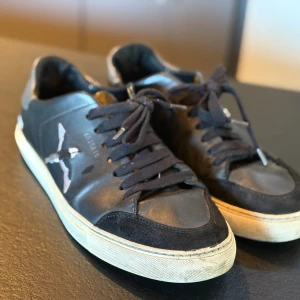 Svarta sneakers från Axel Arigato - Svarta sneakers i skinn från Axel Arigato med broderad fågel på sidan | storlek 41 | Nypris: 2700kr | Mitt pris 349 kr | liten skavank på sulan då den är lite sliten men ingenting som märks av vid användning | hör av er vid vidare frågor😁