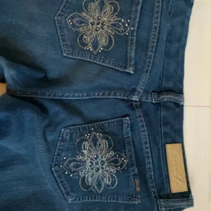 Blå bootcut jeans från Seven7 - Snygga blå bootcut jeans från Seven7 med broderade bakfickor och glittriga detaljer. Jeansen har normal passform och är tillverkade i klassiskt denimtyg. Perfekta för dig som vill ha en cool och unik look med extra detaljer på fickorna. Jag är 167 cm men dem ör lite för korta på mig❤️