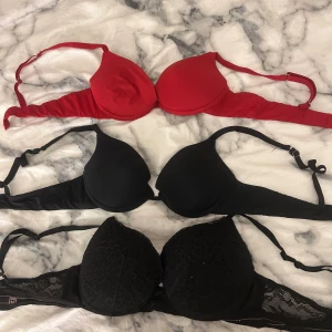 Röd och svarta linnetoppar 80B - Tre snygga linnetoppar i storlek 80B från Viania. En röd med slät yta och två svarta, varav en har spetsdetaljer och den andra är enkel och stilren. Alla har justerbara axelband och mjuka kupor för skön passform. Perfekt för dig som gillar klassiska färger och enkel design. Säljer alla för 100kr 