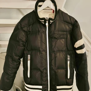 Moncler du jacka. Marinblå. Vintage! - Dunjacka från Moncler. Vintage!Dragkedja framtill och ribbade muddar i mörk marinblå och vitt. Innerficka. Fluffig och riktigt varm för kyliga dagar. Perfekt skick! Endast seriestrippen är liiite tvättsliten. Är förmodligen en herrjacka. Står classe 1 på etikett och en 4 på annat ställe. Skulle säga herr stl M. Dam stl 40. Killen på bilden är M, 175cm lång. Äldre modell så ej QR kod. Fler bilder kan skickas. Hämtas på Hägerstensåsen eller ök 💙 (se gärna alla mina andra annonser oxå). 